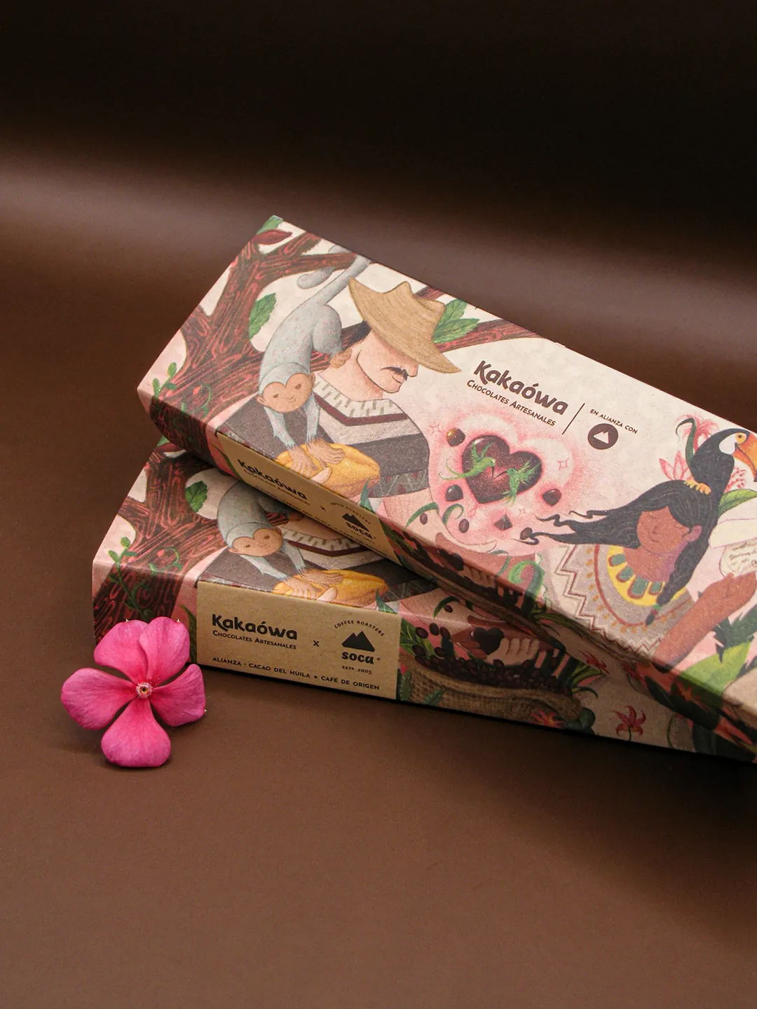Cajas de bombones Kakaówa con una flor rosada sobre fondo oscuro