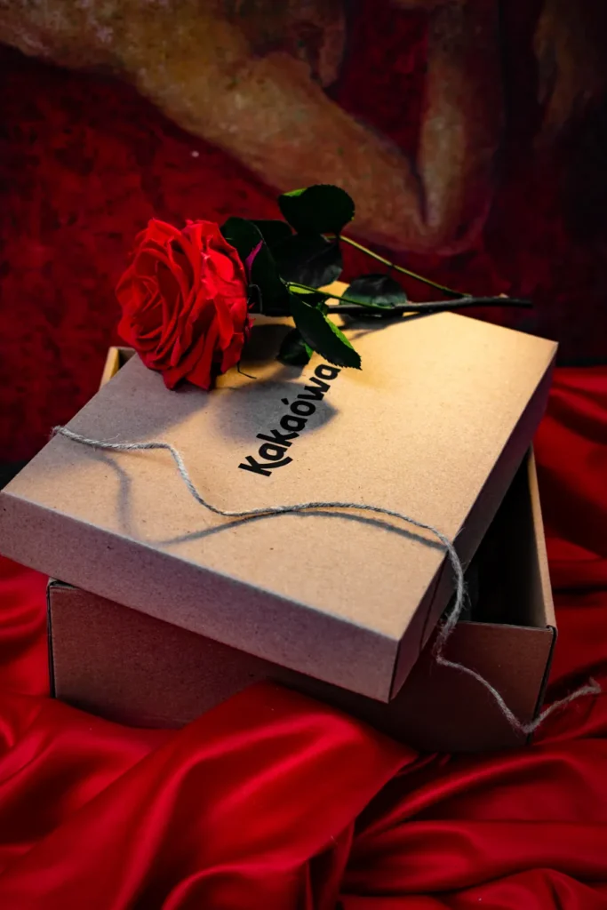 Caja de regalo Kakaówa con una rosa roja sobre satín rojo